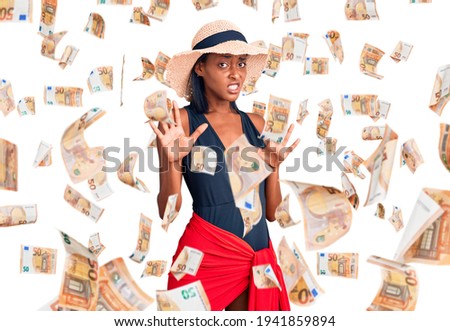 Young african american woman wearing swimsuit and summer hat afraid and terrified with fear expression stop gesture with hands, shouting in shock. panic concept.