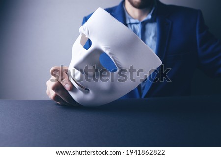 Businessman holding white mask in his hand Royalty-Free Stock Photo #1941862822