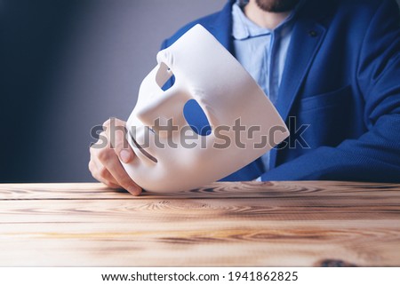 Businessman holding white mask in his hand Royalty-Free Stock Photo #1941862825