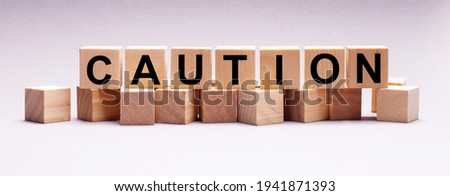 On a light background, wooden cubes with the text CAUTION