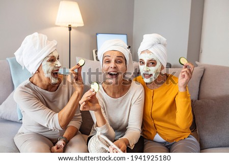 Three mature happy women with face masks at home. Friendship and wellbeing concept. Pretty mature female friends having spa day. Natural homemade facial mask. 