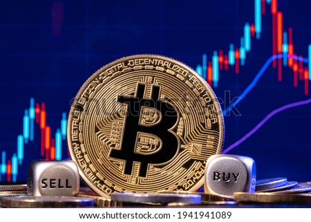 A golden bitcoin with two dices in a pile of coins on the background  the stock chart with candlesticks. On the edges of the dices are the words "buy" and "sell". The concept of buy-sell choice.