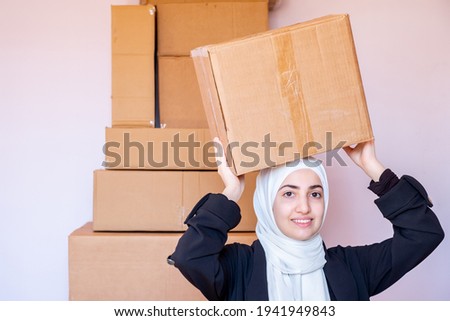 Arabic muslim woman holding carton boxes in her hand