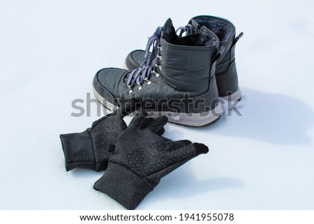 Gray snow boots, with winter gloves in  snow background.