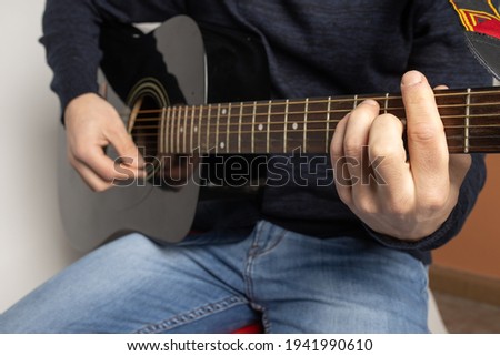 young man playing black acoustic guitar on the white background