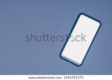 Smartphone mockup with white screen. Close-up phone lies on a gray background. View from top