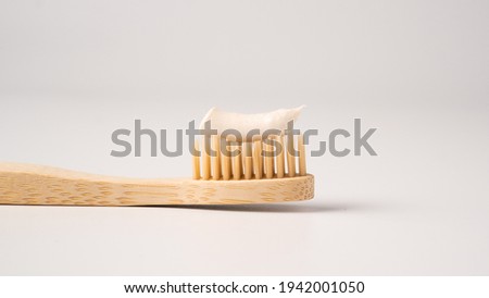 Wooden eco toothbrush with toothpaste on a white background. Bamboo toothbrush. Royalty-Free Stock Photo #1942001050
