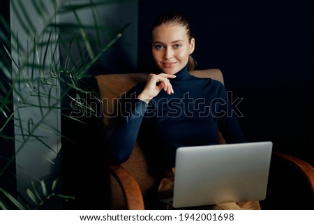 Office clothes, favorite coworking job. Works on a laptop computer. Portrait of a confident young woman European appearance brown-haired.