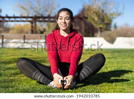 Young woman sitting and stretching in butterfly position in a park