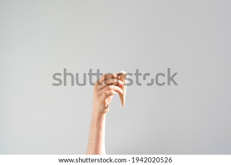 human hand holding ice cream cone isolated on color pastel background, abstract creative idea