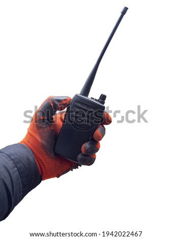 A man holds a black portable radio station in his hand with a red glove. The photo is isolated on a white background. The concept of news about shoplifting, the work of security guards.