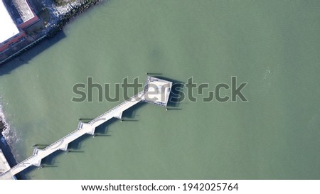 A top down shot over a long pier in the green waters of Red Hook Channel on a sunny morning.