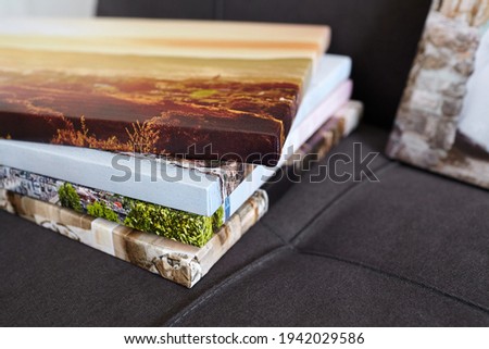 Canvas prints. Photo printed on canvas with gallery wrapping on stretcher bar. Different photos stacked on sofa. Colorful photography