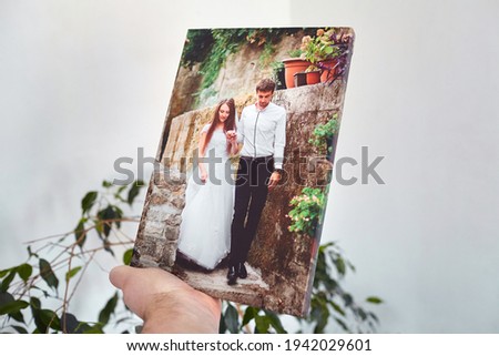Canvas print stretched on stretcher bar with gallery wrap, hand holds wedding photography, photo printed on canvas in white wall room