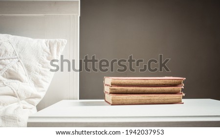 books on retro white table by bed    Scandinavian interior  neutral color palette.