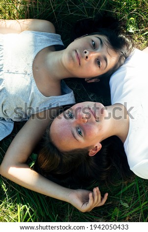Two teen girl lying on the green grass.