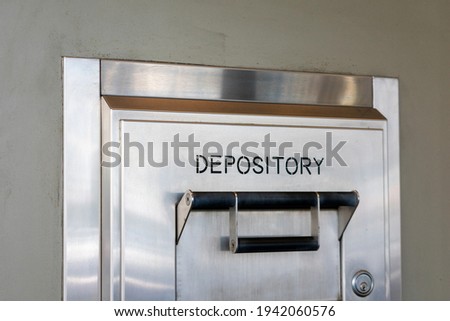 Depository sign on an exterior secured bank drop box attached to the wall of a bank building Royalty-Free Stock Photo #1942060576
