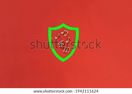 Knight's shield of green color, wooden notes on a red background. The concept of copyright protection. Musical creativity.