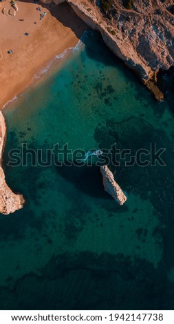 An aerial shot of the sea surrounded by cliffs under the sunlight in Algarve, Portugal
