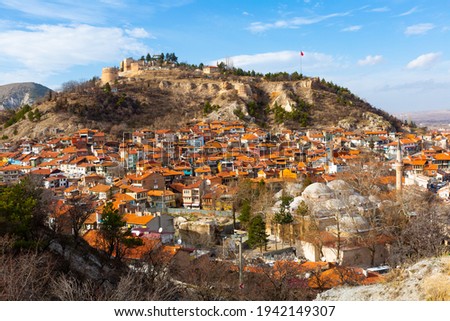 Scenic view of residential districts of Turkish city of Kutahya on background of hill with ruined Byzantine castle on top on sunny winter day