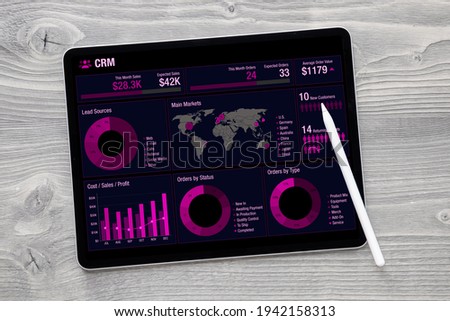 Business data analytics app with charts and infographics on the screen of tablet computer