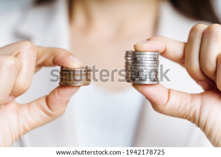 Hands compare two piles of coins of different sizes. Royalty-Free Stock Photo #1942178725