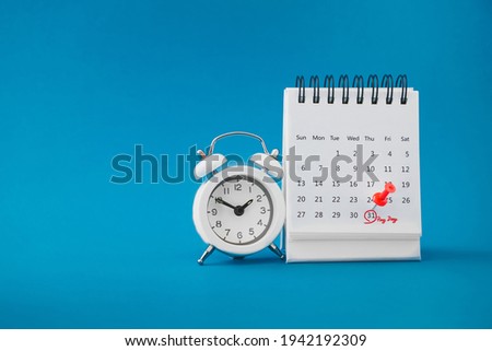 red thumbtack pin on the last day  of month with circle and pay day word near white analog clock on grunge blue background for business and finance concept Royalty-Free Stock Photo #1942192309
