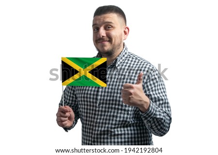 White guy holding a flag of Jamaica and shows the class by hand isolated on a white background. Like for Jamaica.