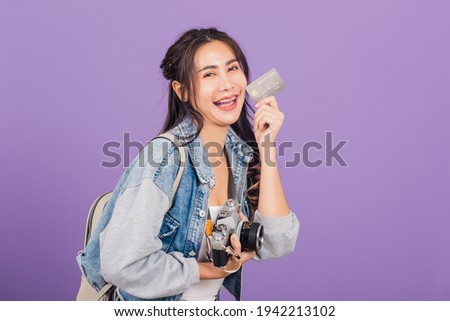 Happy Asian portrait beautiful young woman excited smiling photographer holding debit credit card bank and retro vintage photo camera ready travel isolated on purple background, tourism and vacation