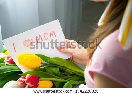 I love mom card drawing by child for Mother`s Day with yellow tulip flowers in hands of woman. Happy Birthday or Mother`s Day greetings and congratulations to mommy.