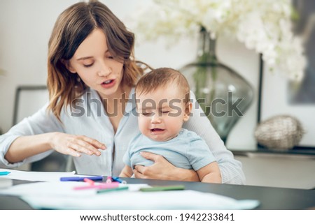Young mother soothing crying baby sitting at table