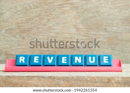 Tile alphabet letter with word revenue in red color rack on wood background