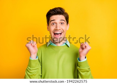 Photo of young excited crazy smiling positive good mood man hold fists in victory isolated on yellow color background