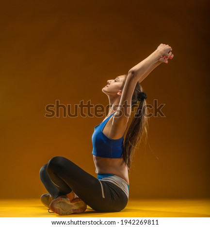 Young happy fitness girl with sporty body posing at studio on a yellow background. Beautiful fit Girl jumping. Fitness model in sportswear holding elastic band. Weight Loss. Healthy lifestyle. Sporty