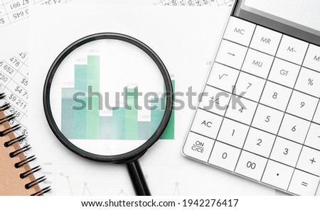 Close up of pen on notepad, business documents calculator with magnifying glass in background.Business concept photo with sunlight filter effect.
