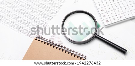 Close up of pen on notepad, business documents calculator with magnifying glass in background.Business concept photo with sunlight filter effect.