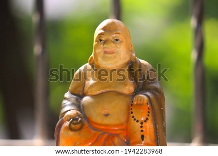 Beautiful small sculpture of laughing buddha Royalty-Free Stock Photo #1942283968
