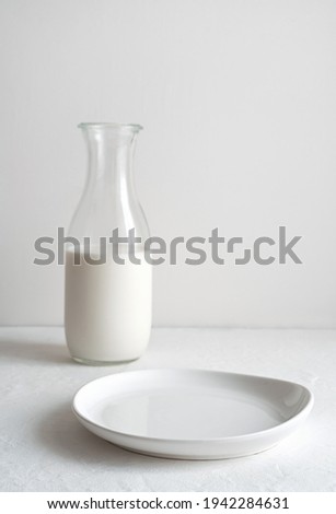 Minimalistic vintage background with an empty plate and a jug of milk in the background. Side view with copy space. A concept for your design.