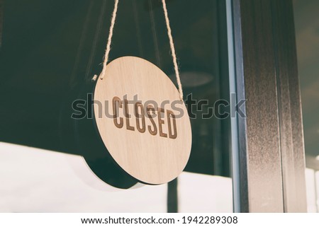 The wooden sign with text: Closed hanging on the door in cafe