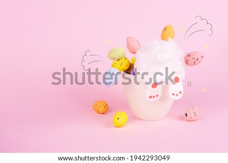 Easter bunny digs in a pot of eggs. Funny background for the holiday Easter. The hare's butt is sticking out of the basket. Multi-colored eggs fly in different directions. Cheerful holiday concept