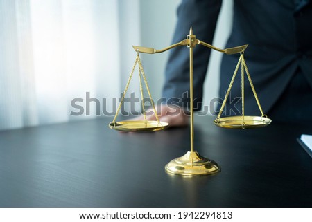 Lawyer or judge standing at the table near scale balance in the law firm