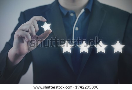 Businessman hand holding five star symbol to increase rating of company concept.