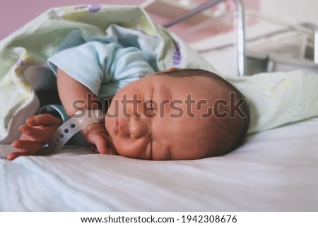 Newborn baby peacefully sleeping in hospital room after delivery. First days life of baby after birth.
