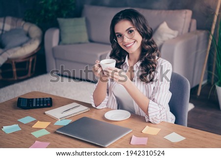 Photo of optimistic brunette curly hairdo lady drink coffee from home wear white shirt sit by table