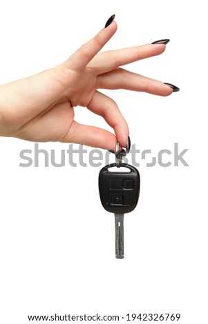 A female hand with a black nails manicure holds a black car key with her fingers. Car sharing concept. Isolated on white background.