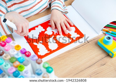 The child draws animals through a stencil. Toddler early preschool education. Royalty-Free Stock Photo #1942326808