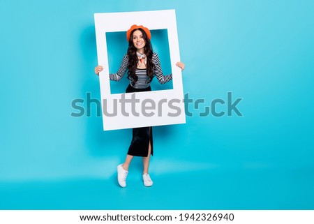 Full length portrait of positive young girl hands hold paper frame have good mood isolated on blue color background