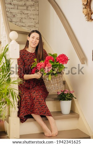 Woman has beautiful flowers at home on the stairs.Beautiful home with red hydrangeas. Small business owner offers flowers for the garden for sale. Florist makes photos and videos for her online blog. 