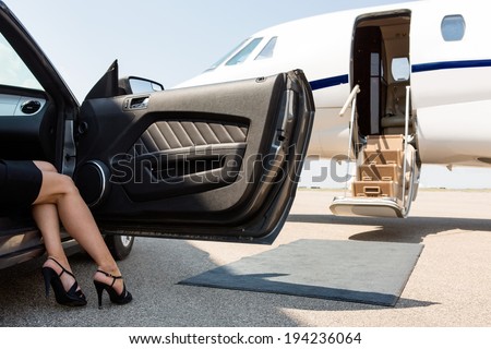 Low section of wealthy woman stepping out of car parked in front of private plane Royalty-Free Stock Photo #194236064