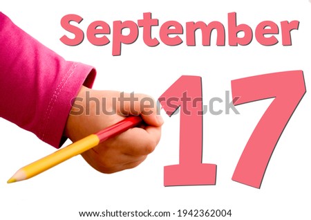 Children's hand writes September 17 in red pencil on white background. Business and leisure concept